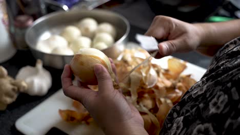 toma pov de las manos de un chef pelando hábilmente la piel de las cebollas frescas mientras la mujer prepara las verduras antes de cocinarlas