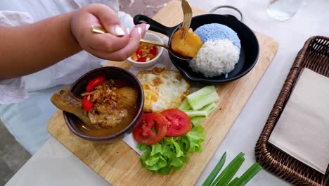 person savoring chicken massaman curry with rice