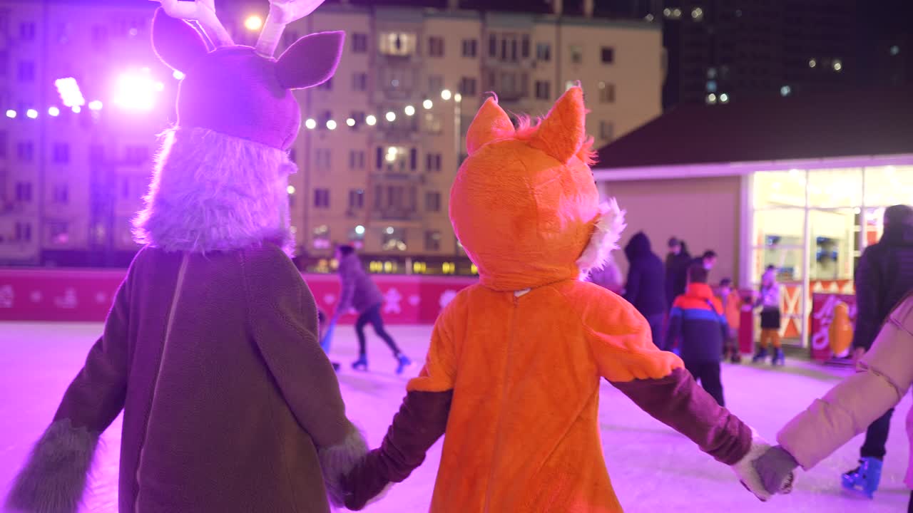 niños con disfraces de animales patinando sobre hielo por la noche