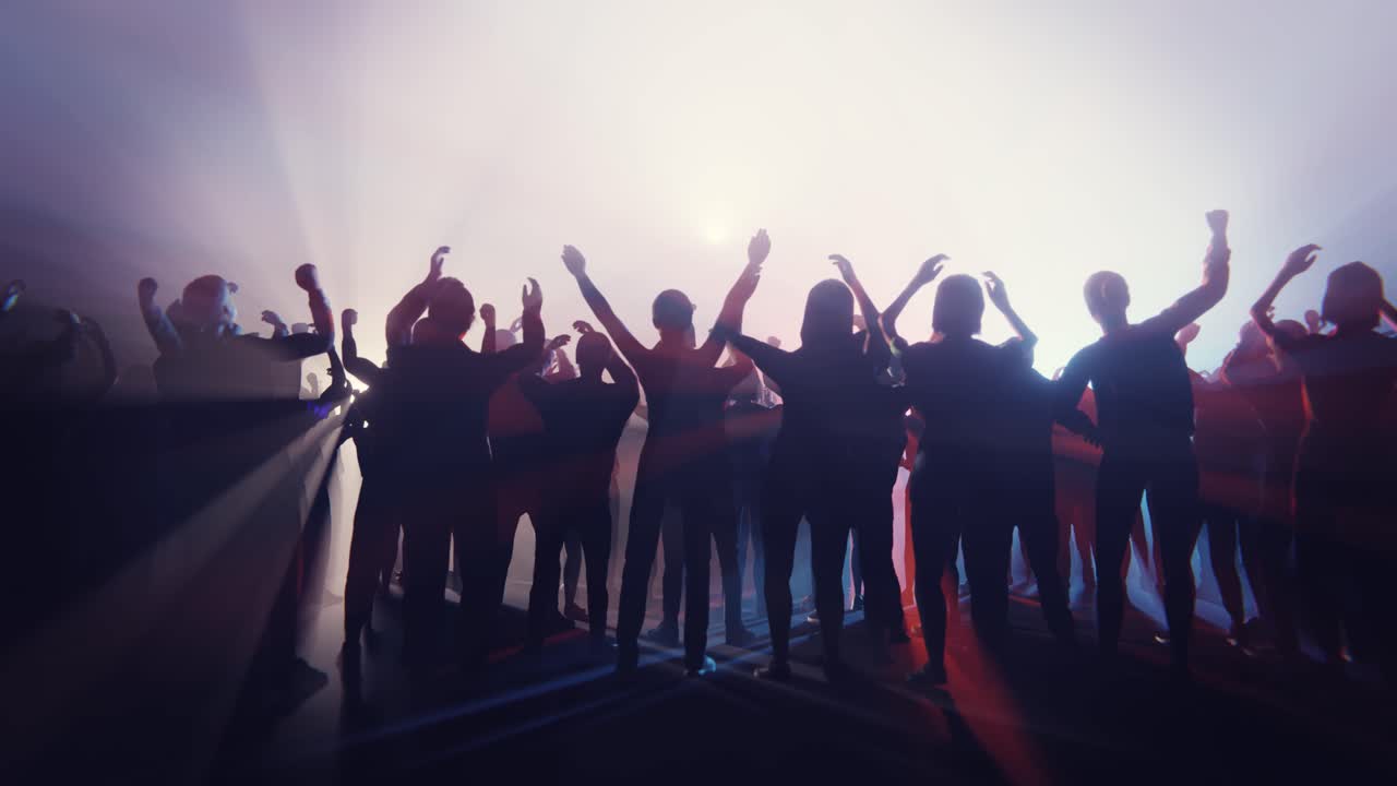 Backlit Silhouettes of People Raising Hands in a Celebratory Crowd