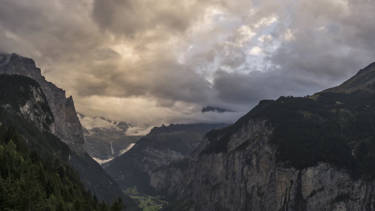 Time Lapse of clouds rolling through vibrant green cliff valley in Switzerland at sunset. Multiple distant waterfalls. Shot in Lauterbrunnen Switzerland, near Zermatt.