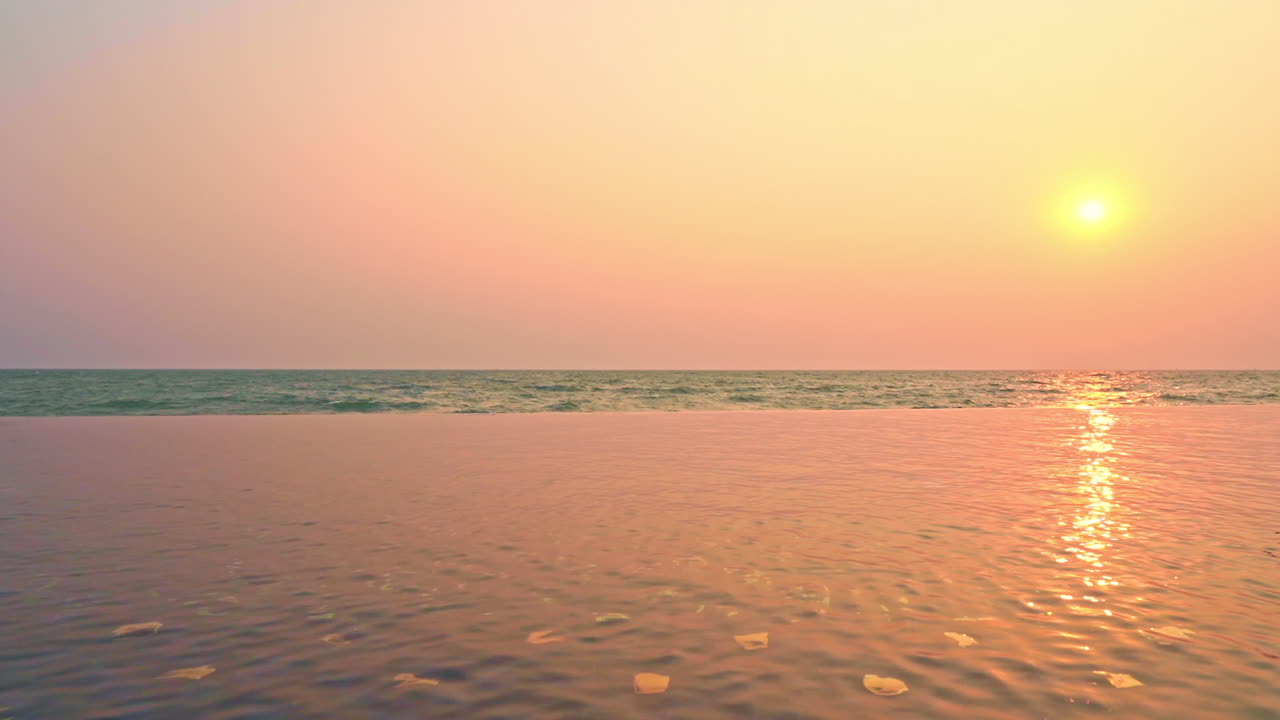 Summertime: beautiful view of the sunset at the infinity pool area. Sunlight reflections in pool water