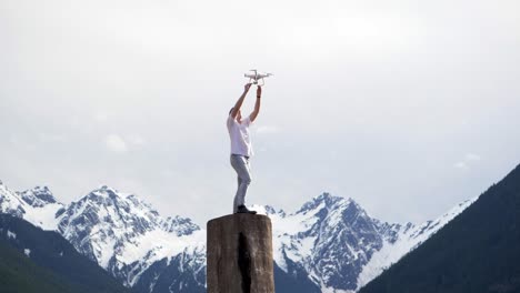 slow motion shot of person releasing drone from hands in front of distant mountains
