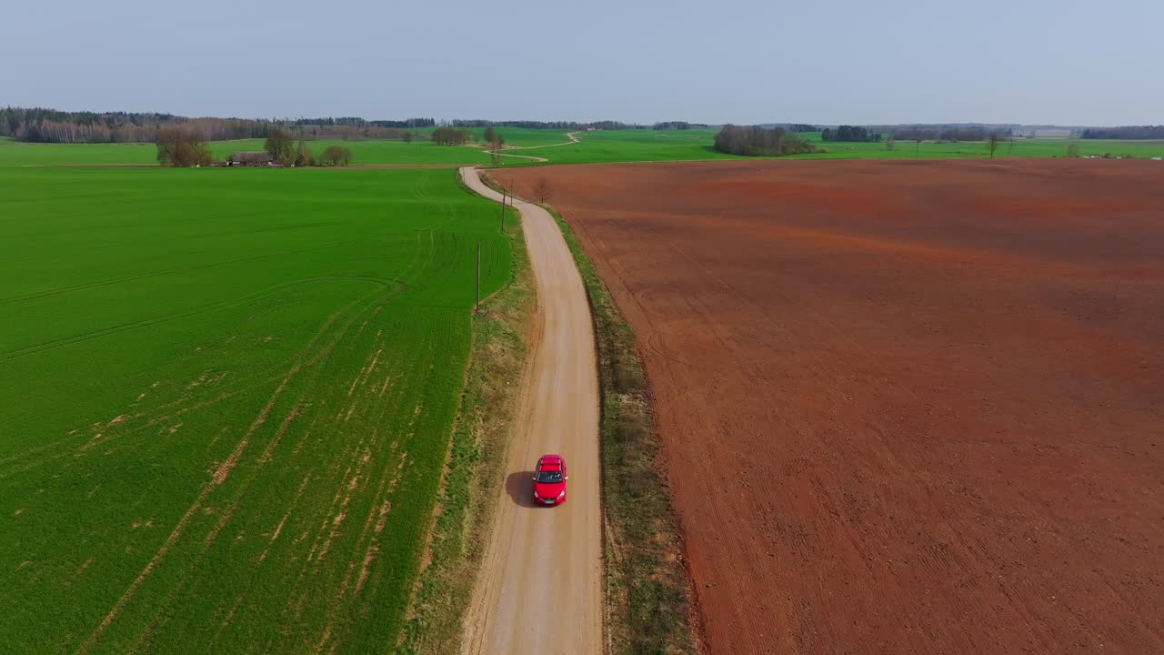 Vibrant green and brown fields frame rural drive on quiet Latvian backroad