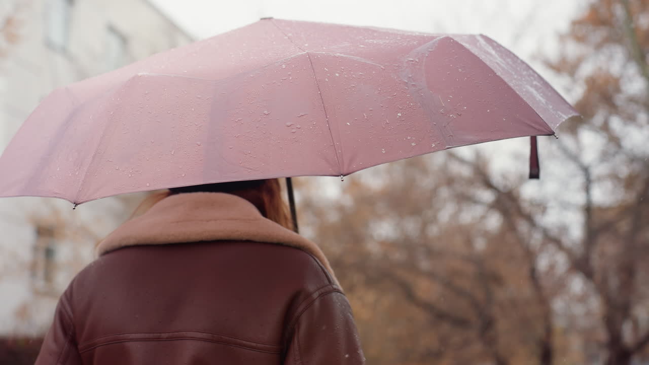 Shot of umbrella over person s head, wearing knit cap, brown shearling jacket, capturing peaceful winter scene with snowflakes falling gently around, showcasing tranquil cold weather atmosphere