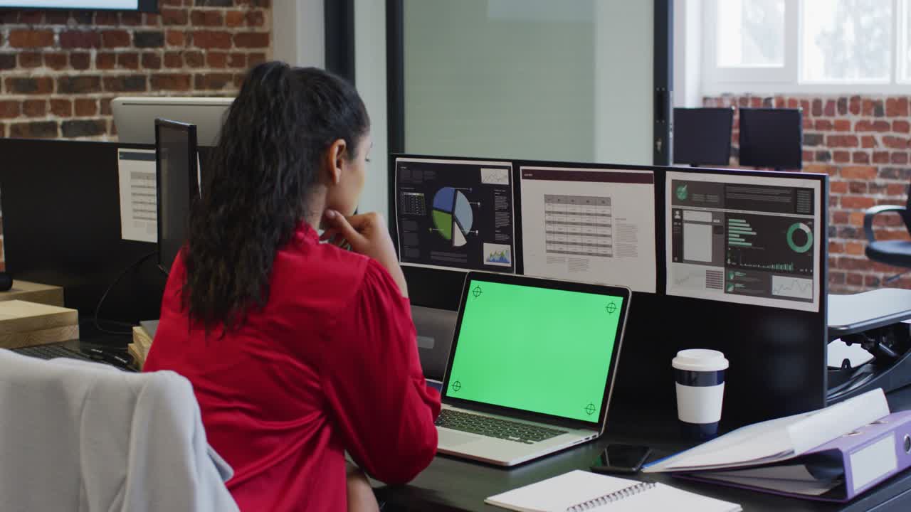 mujer usando una computadora portátil mientras está sentada en su escritorio en la oficina