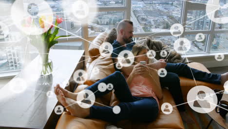 animation of network of connections with people icons over caucasian couple using smartphones