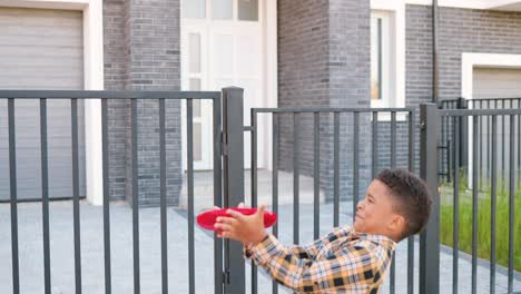 afro-amerikaanse ouders spelen frisbee met kleine schattige zoon buiten in huis in buitenwijk