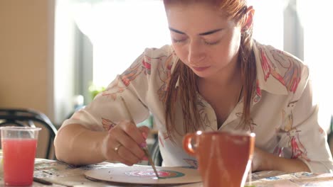 woman painting a wooden disc