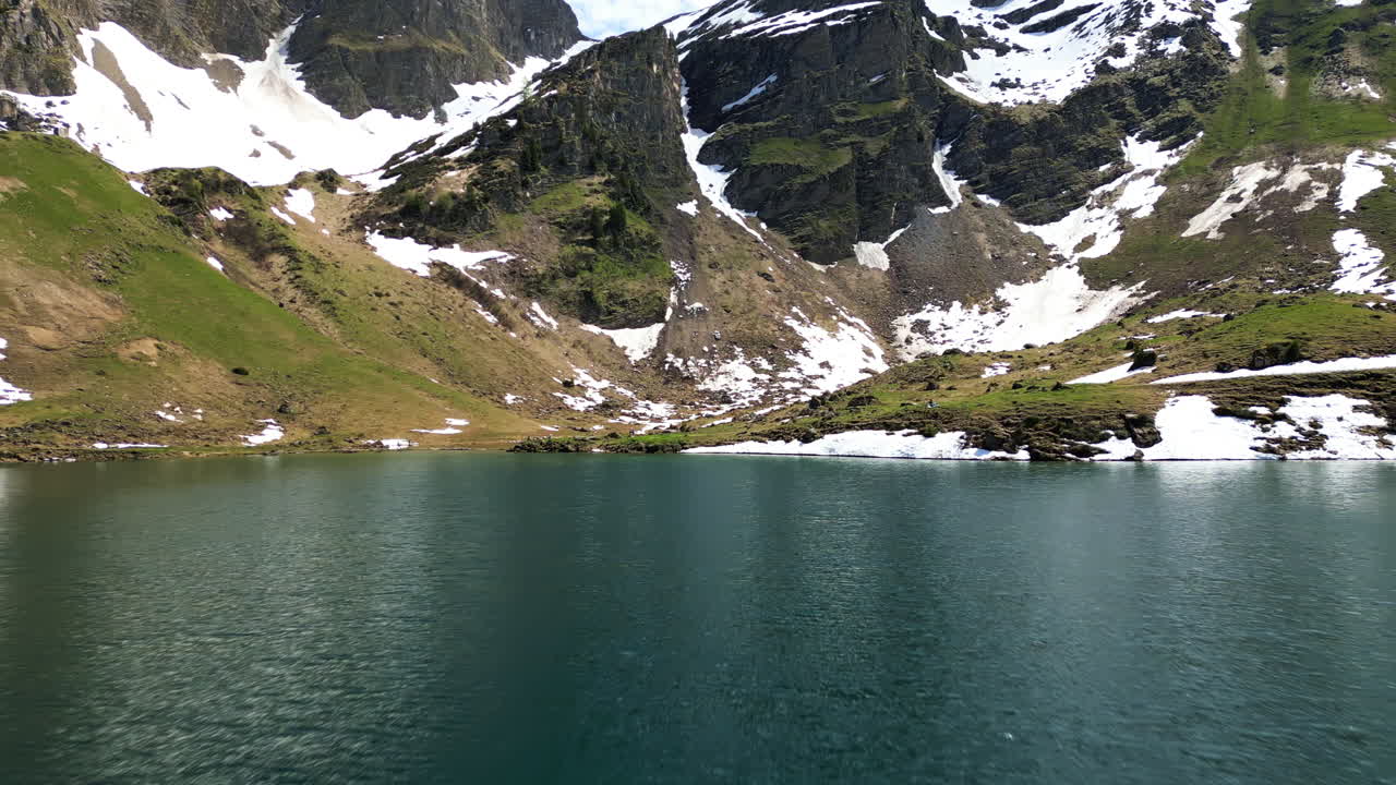 Aerial: Lake Lioson during the day with snow in Ormont-Dessous, near Les Mosses, in the canton of Vaud, Switzerland, push in drone shot