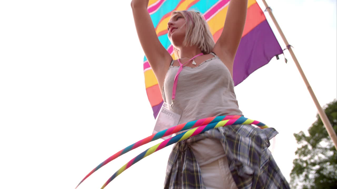 Ragazza che fa hula hoop con due cerchi a un festival, al rallentatore