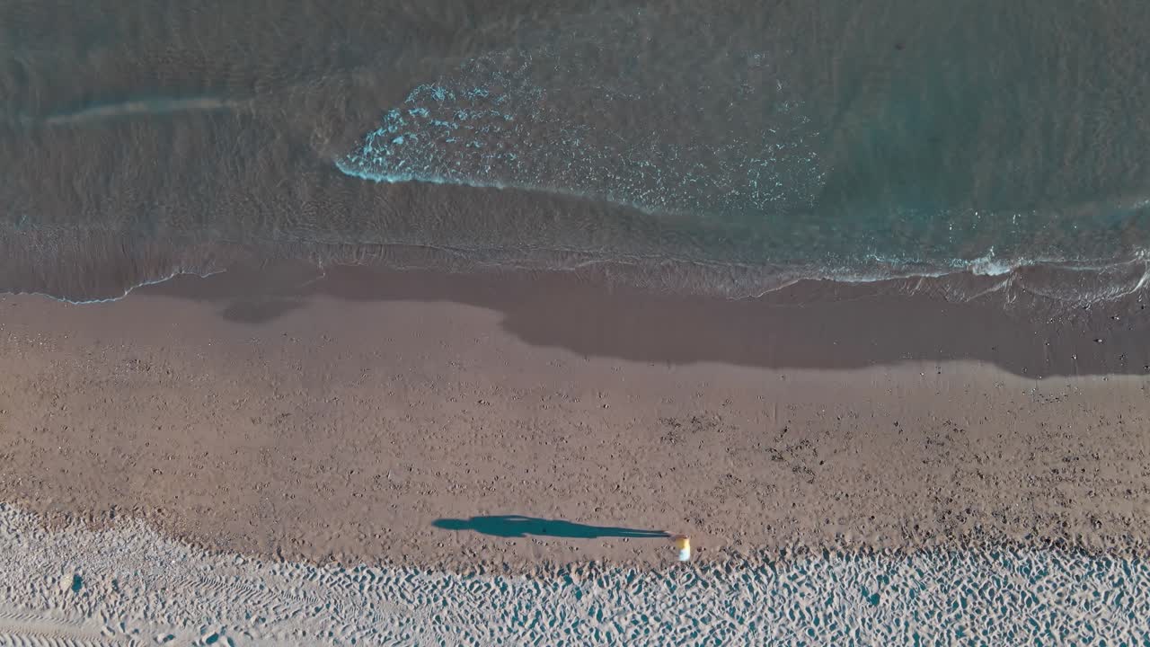 Aerial static high angle view of woman jogging at the beach