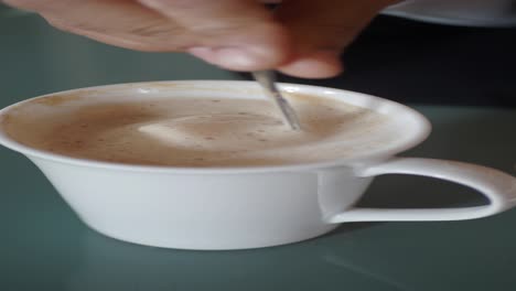 person stirring coffee in a cup