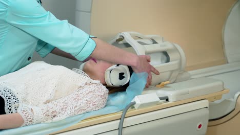 female patient lays in a mri scanner. nurse prepares the patient before making tomographic scanning. modern medical equipment in clinic.