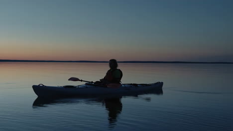 a lone kayaker on a serene lake at dusk