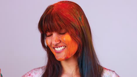 hermosa estudiante india pintada en colores celebrando el festival de holi en el estudio fondo aislado blanco