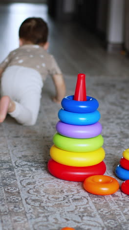 little kid crawls away from toys on the floor. baby leaves his pyramids, then stands up and runs away. blurred backdrop. vertical video