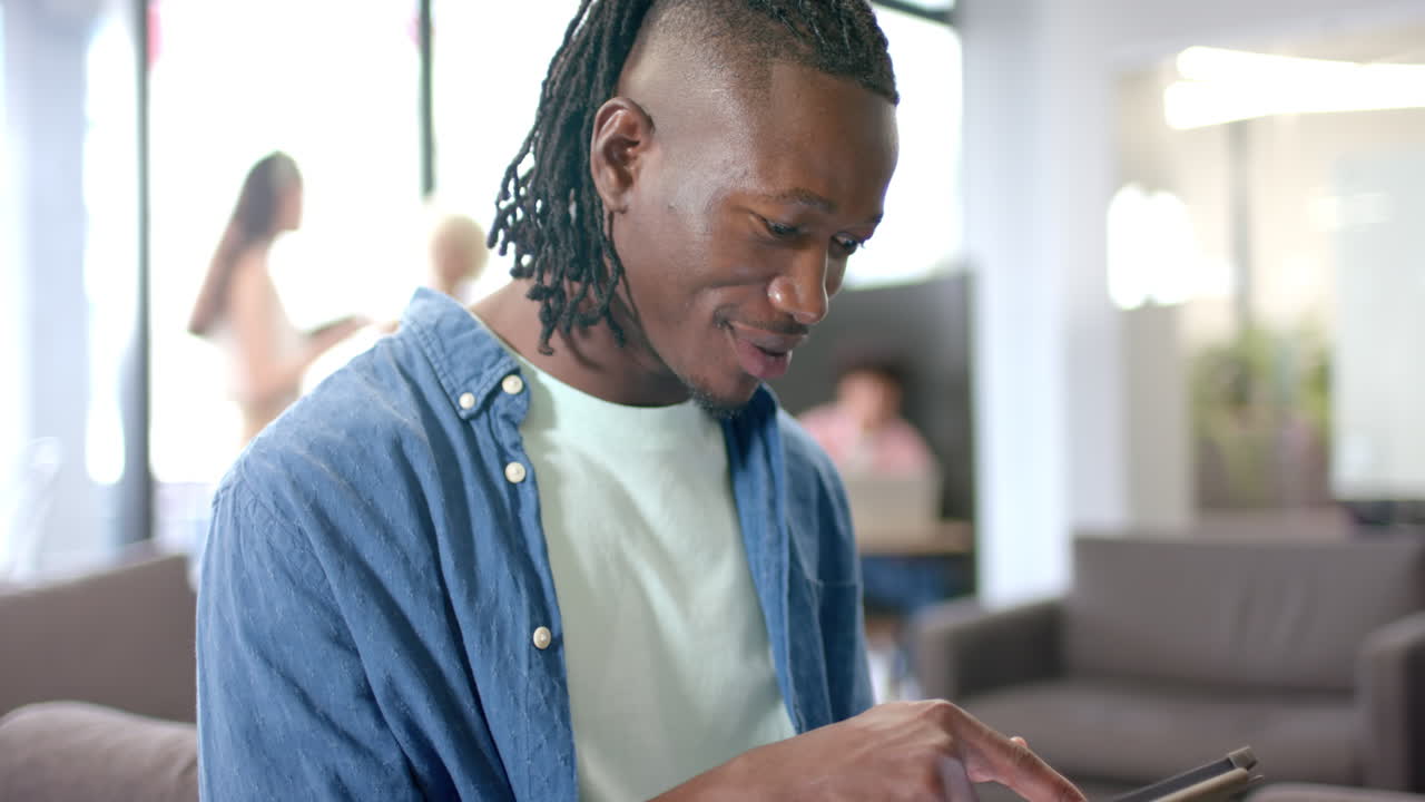 Smiling man using smartphone while sitting in modern office lounge area