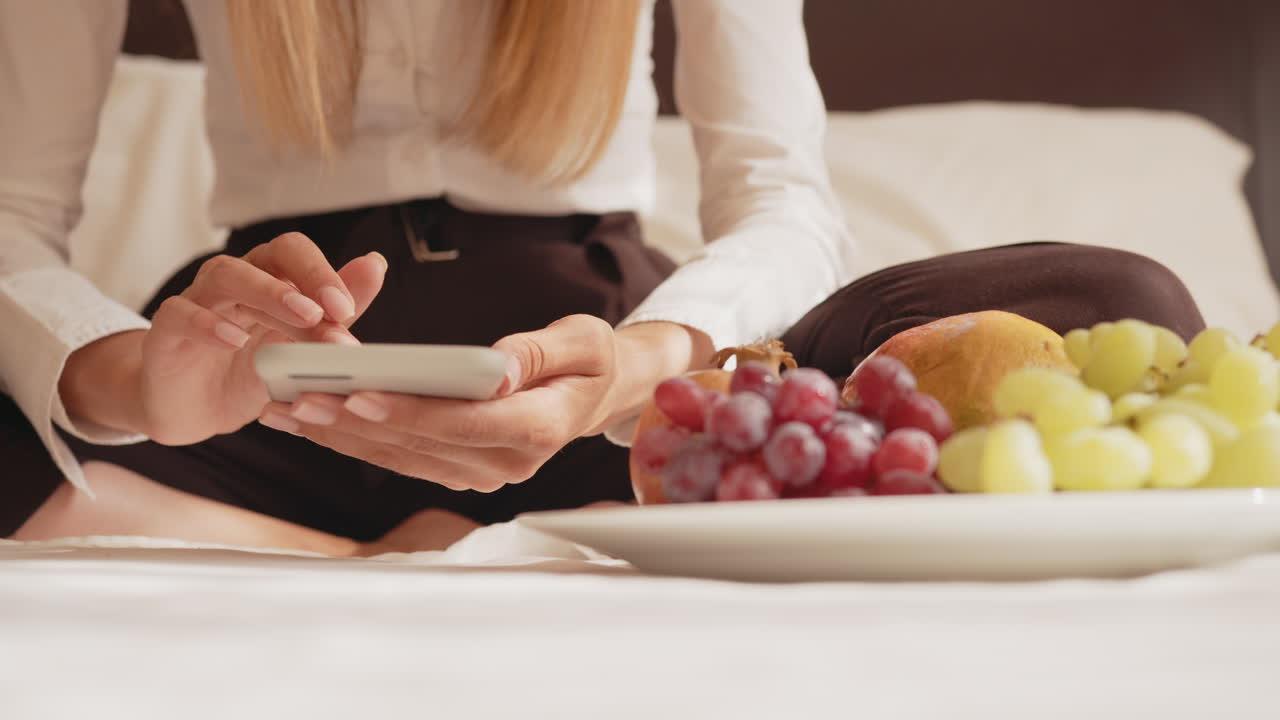 mujer usando el teléfono en la habitación del hotel con el desayuno