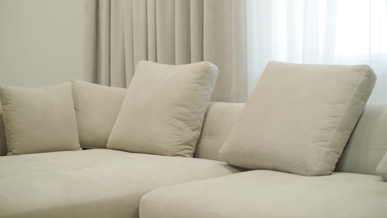 acogedor sofá beige con cojines de peluche en la sala de estar moderna