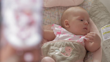 mother taking mobile photo of baby daughter in bouncy seat