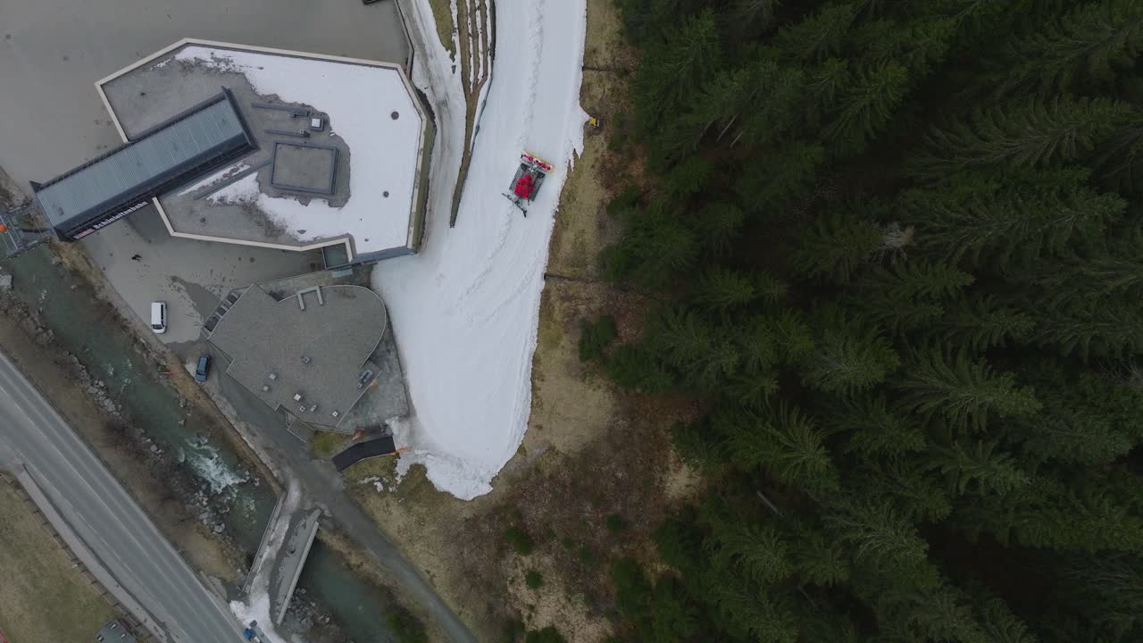 estación de esquí de saalbach-hinterglemm, rodeada de pinos y manchas de nieve, día nublado, vista aérea