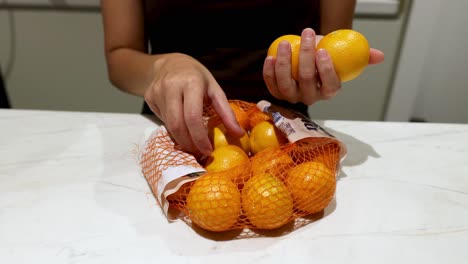 individual arranging oranges from a mesh bag