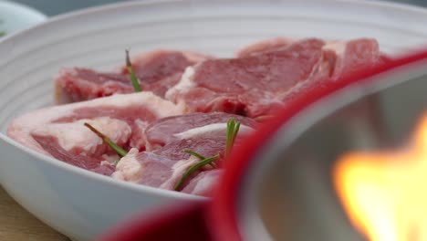 lamb chops ready to be grilled on a red bucket barbeque