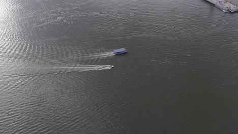 aerial footage of a ferry and a speedboat travelling to hussain sagar lake's buddha statue of hyderabad early morning sun rise and reflection in the water granite rock was used to create the statue