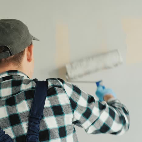 male builder paints wall with roller