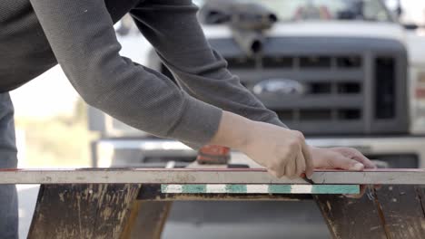 Carpenter-hands-using-pen-and-ruler-or-straight-edge-to-mark-plank,-close-up