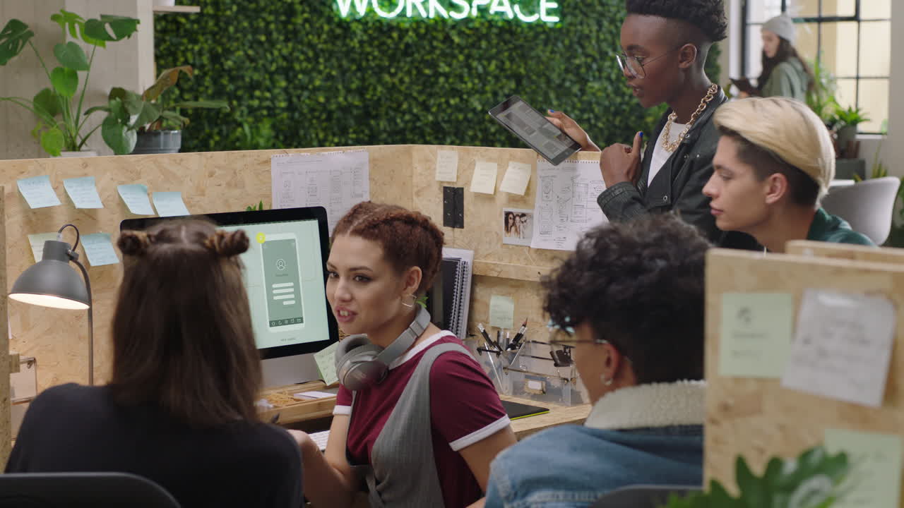 jóvenes empresarios que se reúnen con un equipo de desarrolladores de software que diseñan aplicaciones móviles un grupo diverso de estudiantes que intercambian ideas creativas para la comunicación utilizando la computadora en una oficina de moda