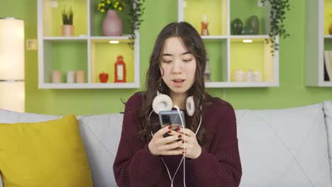 Cheerful-Asian-young-woman-listening-to-music.