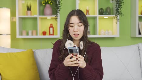 즐거운 아시아 젊은 여성이 음악을 듣고 있습니다.