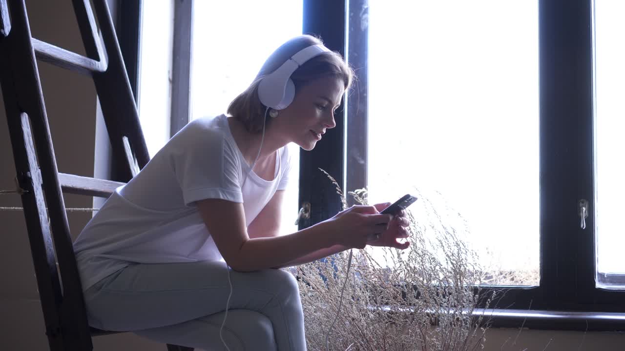 창문 근처에 앉아있는 동안 전화를 사용하는 매력적인 소녀