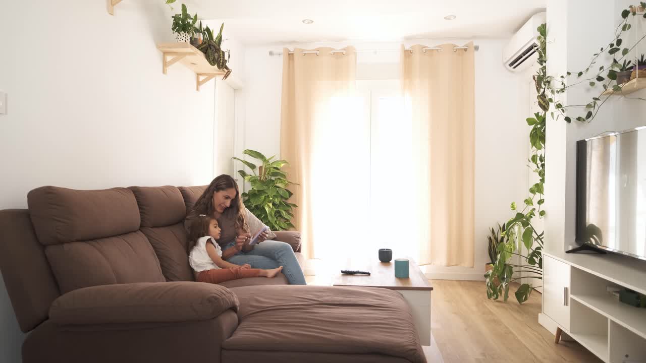 Evde kanepede akıllı telefon kullanan anne ve kızı