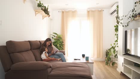 mother and daughter using smartphone on sofa at home