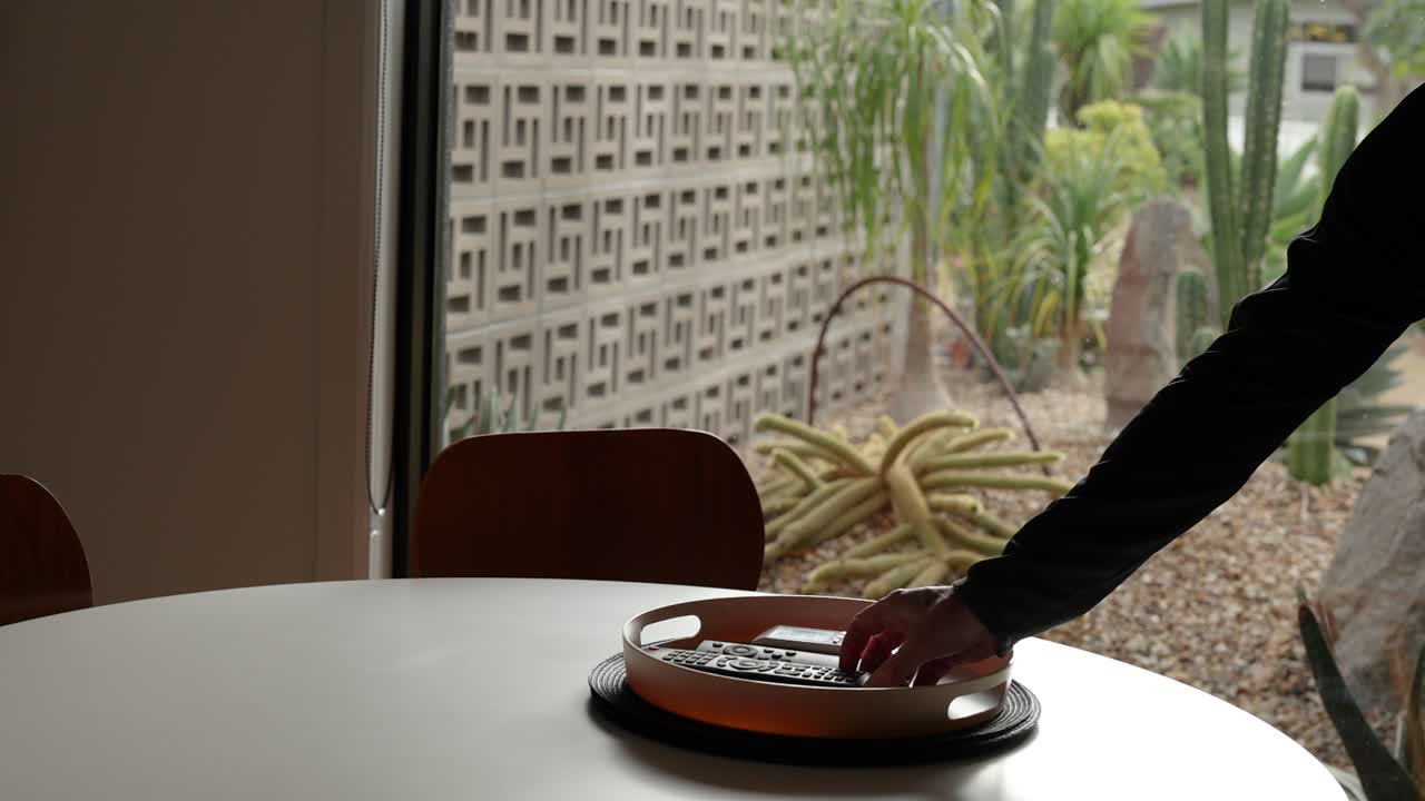 la mano alcanzando y recogiendo el control remoto