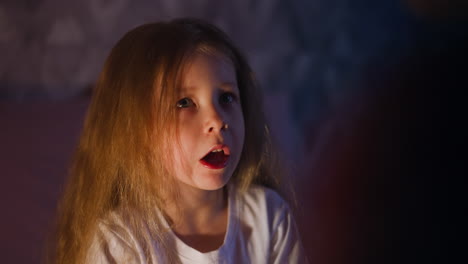 little daughter talks to parent in semidark room at night