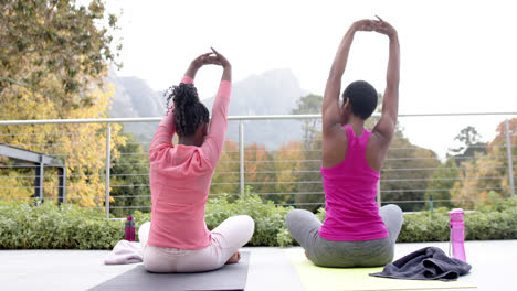 Happy-african-american-daughter-and-mother-practicing-yoga-in-sunnny-garden,-slow-motion