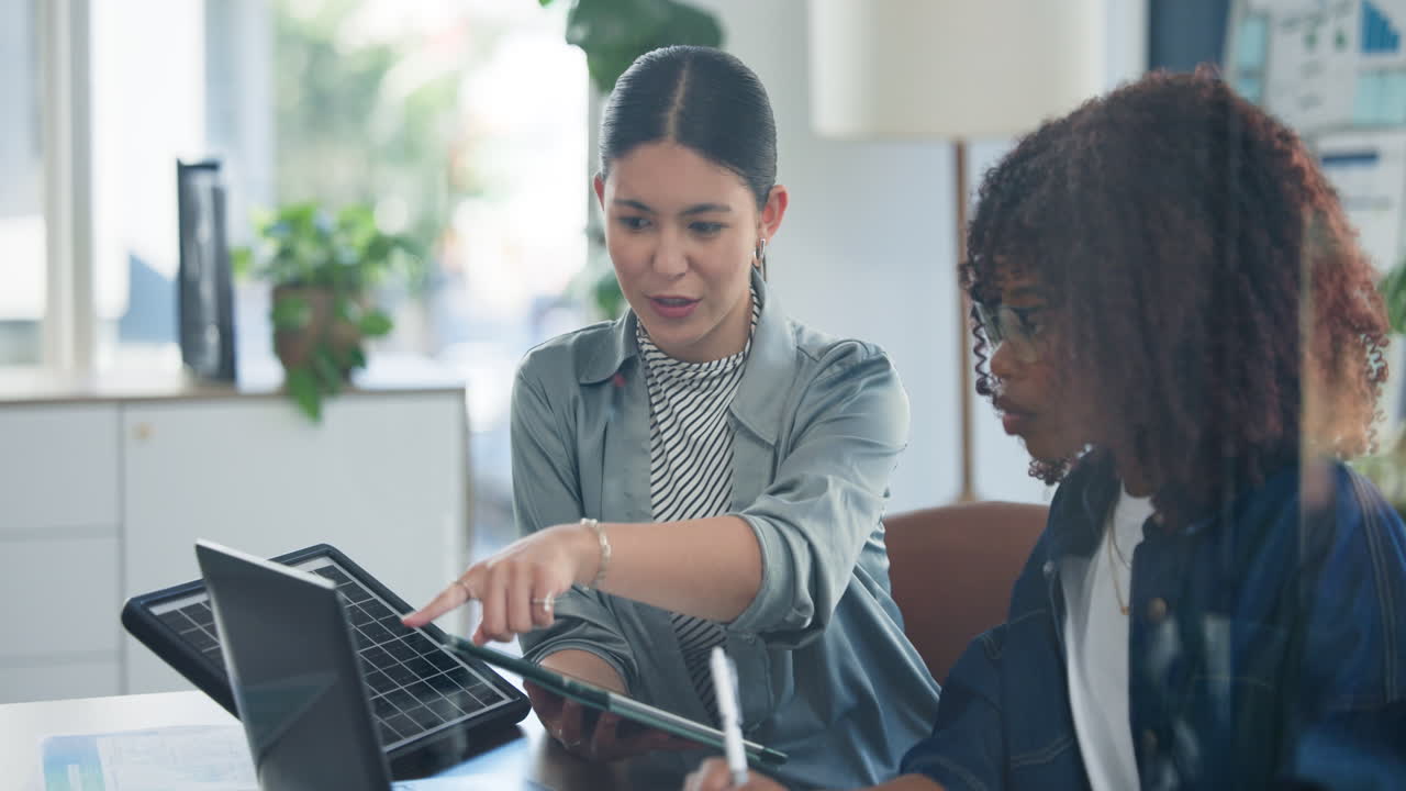 Two Diverse Businesswomen Discussing Solar Energy Solutions in Office
