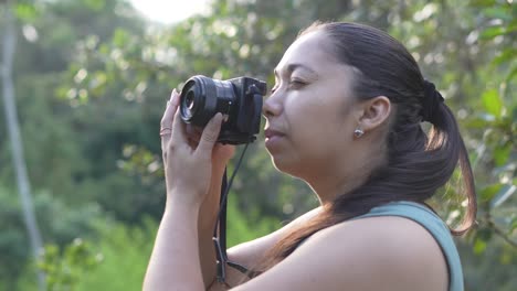 photographer woman with a camera in her hands, taking photographs outdoors surrounded by nature in the forest