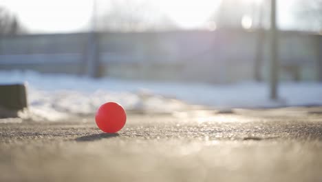 small red ball on icy pavement in winter