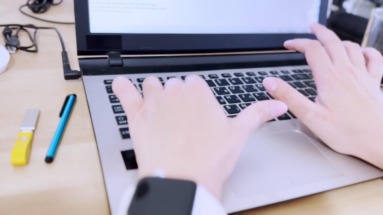 Close-up front view of hands actively typing on a laptop keyboard with Hebrew and English characters