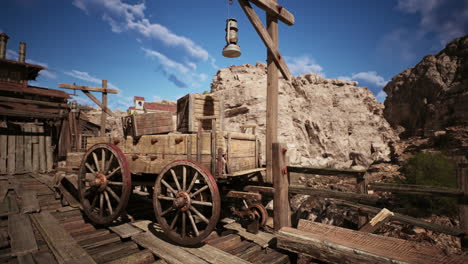 old wooden cart near rustic wooden structures against a rocky backdrop