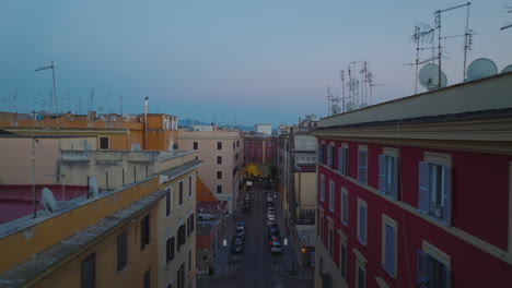 Forwards-fly-above-street-lined-with-multistorey-apartment-houses-with-colour-facades.-Urban-borough-at-dusk.-Rome,-Italy
