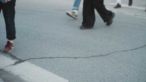 a city view capturing pedestrians walking across the street, with camera focusing on their legs and feet