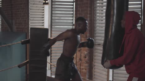 saco de boxeo negro mientras entrena con el entrenador en el club de lucha amateur