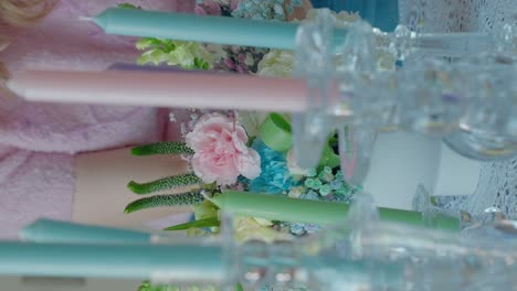 female adult arranging flowers on a decorated table for party event, colored candles