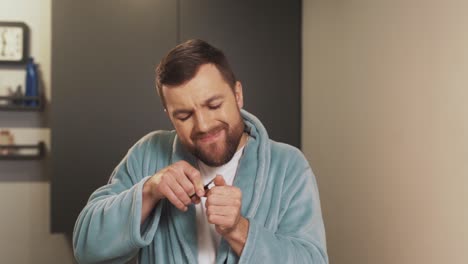 an upset man tries to cut his fingernails neatly, but he doesn't succeed